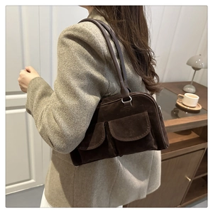 Detail of dark brown suede shoulder bag featuring two front flap pockets and retro style
