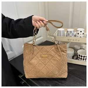 Detail of brown quilted faux suede tote bag with gold chain and brand logo patch