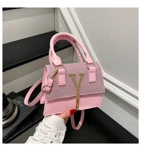 Close-up of pink leather handbag featuring sparkling rhinestones and golden V tassel