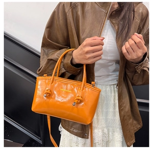 Fashionable bright orange tote bag with knot detail and shoulder strap shown on model