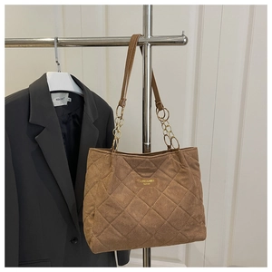 Close-up of coffee brown suede tote bag with quilted diamond pattern and chain strap