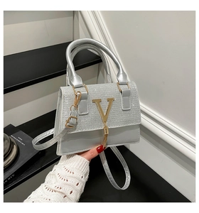 Close-up of silver crossbody bag featuring sequined flap and metallic V-tassel detail