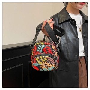Detail of colorful leaf pattern printed crossbody bag with multi-zipper compartments