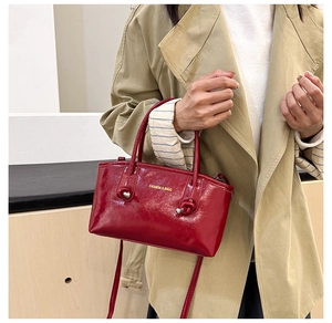 Detail of glossy burgundy leather tote bag with gold lettering and adjustable strap