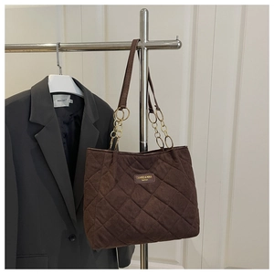 Detail of coffee brown quilted tote bag with diamond stitching and gold chain leather strap