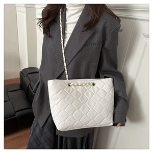 Close-up of quilted white leather tote bag with elegant gold chain strap detail