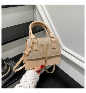 Close-up of beige crossbody bag with sequin texture, gold V logo and tassel detail