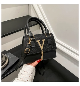 Detail view of black matte leather bag with sequin flap and gold V-shaped tassel charm