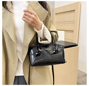 Close-up of black glossy leather tote bag with silver knot detail and fashion logo