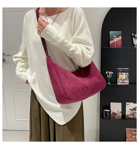 Detail of a magenta suede hobo tote bag featuring a wide shoulder strap in a modern room