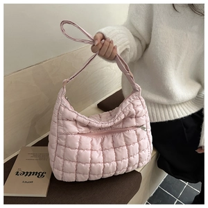 Detailed close-up of pink quilted puffer shoulder bag with grid texture and zipper