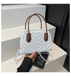 Dettaglio borsa trapuntata bianca con cuciture a V e manico rotondo marrone elegante