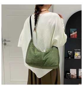 Detail of vintage green suede hobo bag featuring vertical stitching and black shoulder strap