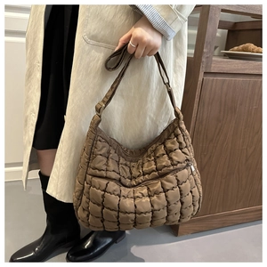 Detail of brown quilted puffer tote bag featuring adjustable strap and glossy nylon fabric
