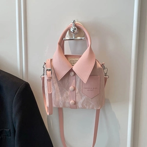 Pink shirt-style handbag with lapel and button detail, hanging on a white wall