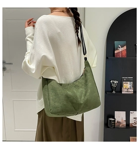 Detail of green frosted suede tote bag with vertical stitching and black leather strap