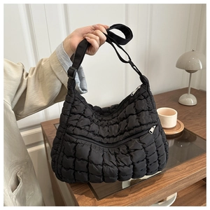 Detail of black quilted puffer bag showing zip pocket and adjustable strap texture