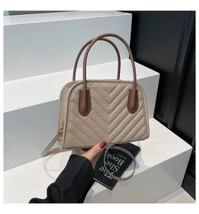 Dettaglio della borsa beige trapuntata con cuciture a V e manici marroni a contrasto