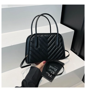 Dettaglio della borsa a mano nera trapuntata a V con cerniera metallica e manici resistenti