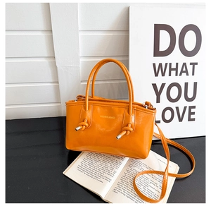 Detail of orange tote bag handle with knot design and gold Fashion & Bags lettering