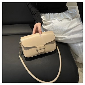 Close-up of minimalist beige shoulder bag with rectangular flap and golden hardware accents