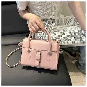 Detail of pink leather handbag with silver horseshoe buckle and adjustable crossbody strap