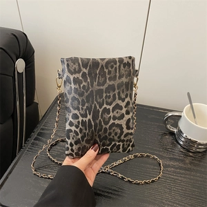 Fashionable leopard print envelope bag with gold chain strap in a lifestyle setting