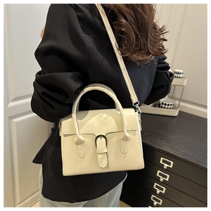 Detail shot of beige leather tote bag featuring vintage metal buckle and adjustable strap