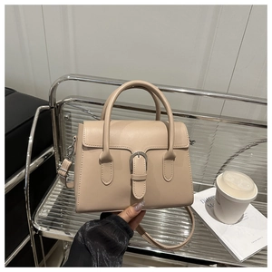 Detail shot of a cream leather handbag with silver buckle and adjustable shoulder strap