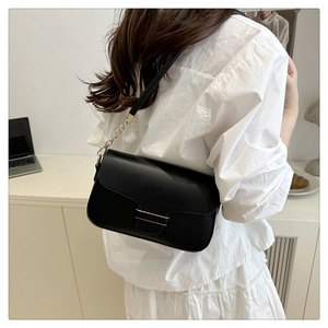 Détail du sac carré en cuir noir minimaliste avec boucle dorée et bandoulière chaîne