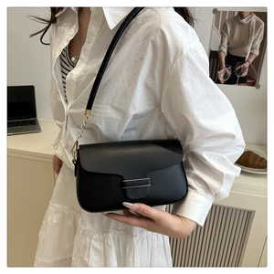 Detail of black leather shoulder bag with gold metal clasp and chain strap accents