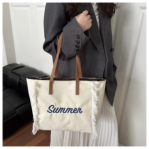 Détail du sac cabas en toile crème avec broderie Summer bleue et longues franges