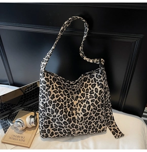Detailed view of leopard print canvas tote bag with fashion label and long shoulder strap