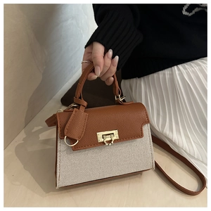 Detail of a brown leather and beige woven crossbody bag with golden rectangular turn-lock