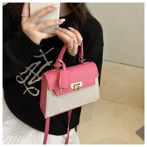 Detail of pink leather and beige canvas crossbody bag featuring a golden square lock