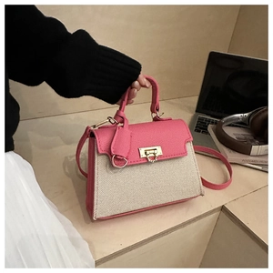 Close-up of pink leather and canvas contrast stitching bag with golden twist-lock closure