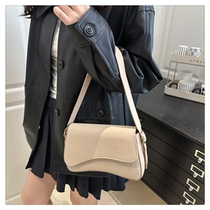 Close-up of beige minimalist faux leather underarm bag with curved flap and long strap