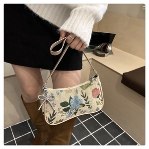 Detail of floral tapestry shoulder bag with silver bow pendant shown in a lifestyle setting
