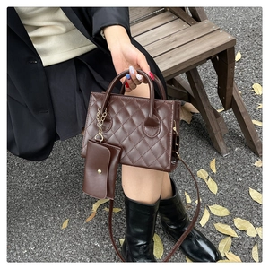 Détail du sac à main matelassé marron avec pochette assortie posé sur un banc en bois