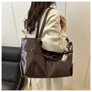 Retro dark brown tote bag in glossy leather shown on shoulder for office commute style