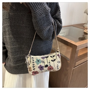 Detail of floral tapestry shoulder bag with metallic chain charm and beige leather trim