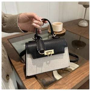 Detail of contrast stitching, lychee grain leather, and gold twist-lock on crossbody bag
