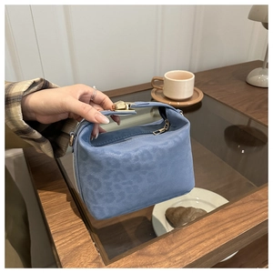 Detail der blauen Handtasche mit Leopardenmuster und Goldschnalle im Café