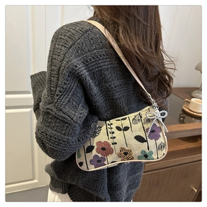 Close-up of floral tapestry underarm bag with beige texture and beaded butterfly charm