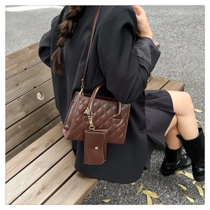 Gros plan d'un sac à main matelassé marron foncé avec une petite pochette assortie sur un banc