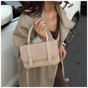 Close-up of beige messenger bag with textured weave pattern and gold hardware details