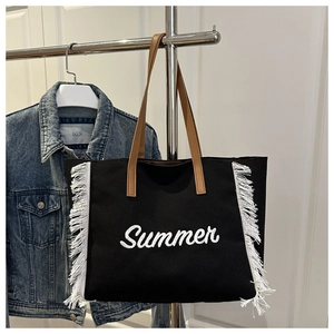 Détail du sac cabas en toile noire avec broderie Summer blanche et longues franges