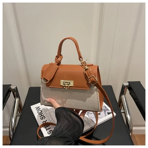 Detail of color-block flap bag featuring brown leather, canvas and gold metal lock