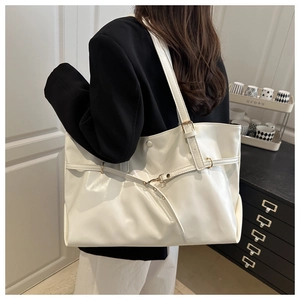 Detail of white glossy tote bag with gold buckle and adjustable strap on a model