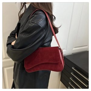 Detail of burgundy shoulder bag with wavy flap design worn with black leather jacket